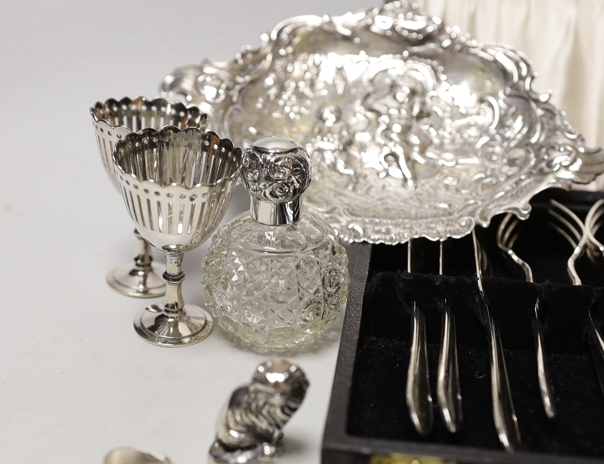 Sundry small silverwares including flatware, a pair of mounted glass scent bottles, a white metal German dish and minor plated items.